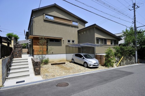 カーキ色の外壁を持つ切妻屋根の駐車場のある家