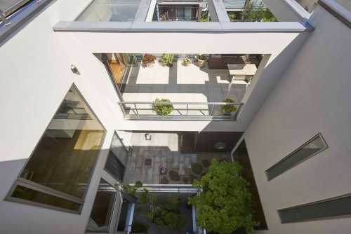 中庭とテラスを見渡せる白を基調とした3階建て住宅