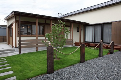 芝生の庭と木製の格子のある平屋風住宅