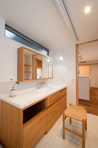 白いカウンターと木製の収納のある洗面所