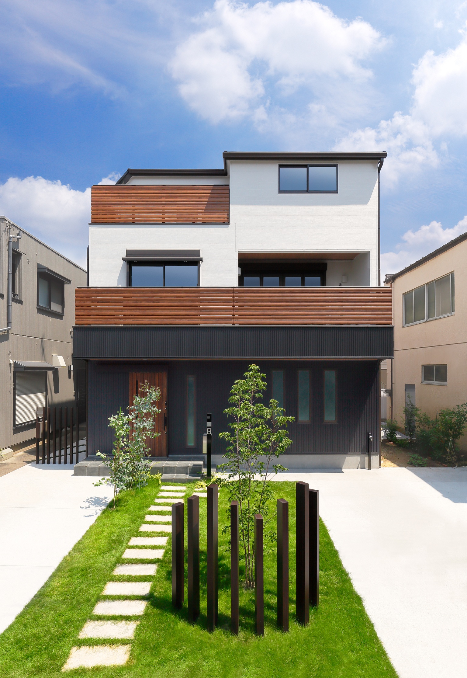 芝生と飛び石の敷かれた2階建ての家