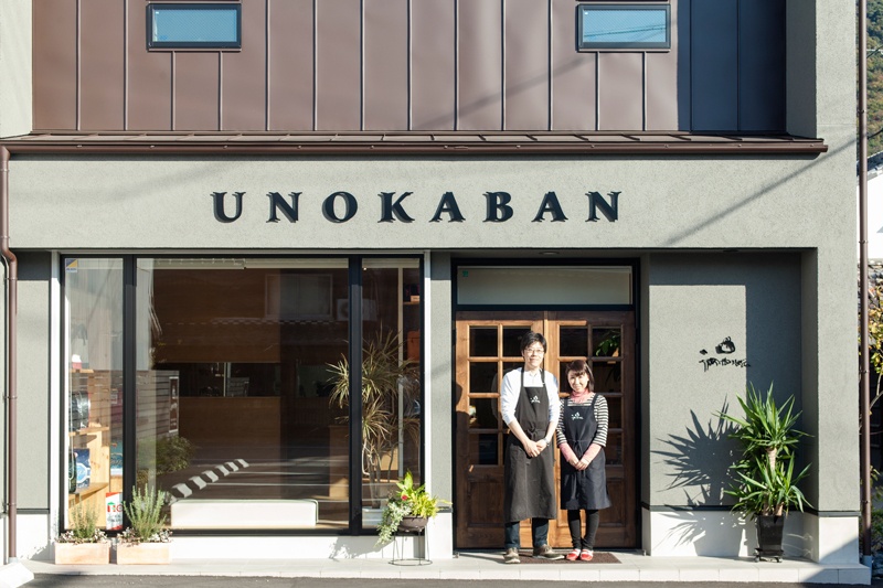 鞄店の店舗の前に立つ夫婦・工務店