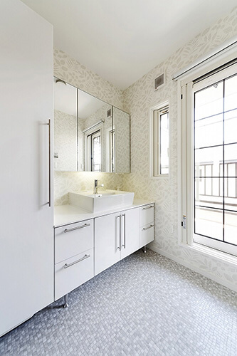 タイルの床とボタニカルな壁紙の洗面所