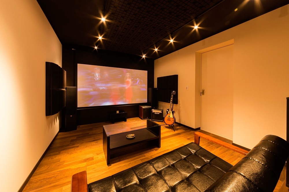 シンプルなデザインのシアタールーム、大きなスクリーンとギター