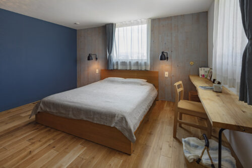 ダブルベッドの置かれたブルーの壁の自然光の入る寝室