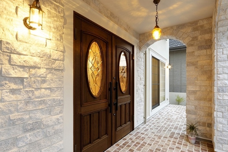 無垢の玄関ドアが存在感を放つ白い石貼りの家