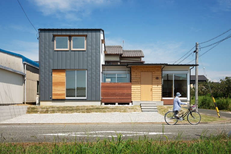 硬質な雰囲気の2階建て部分に、柔らかさ、素朴さを感じる平屋部分が接続された外観