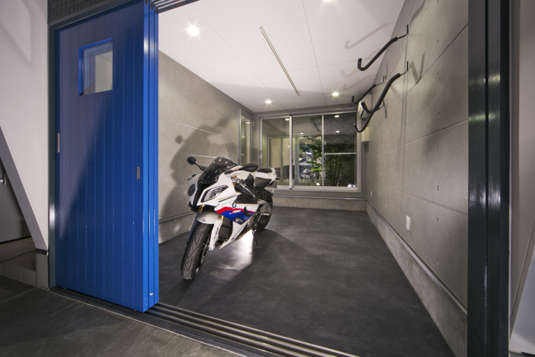 青い扉を建物のアクセントにし、駐車場を開放的な空間に演出