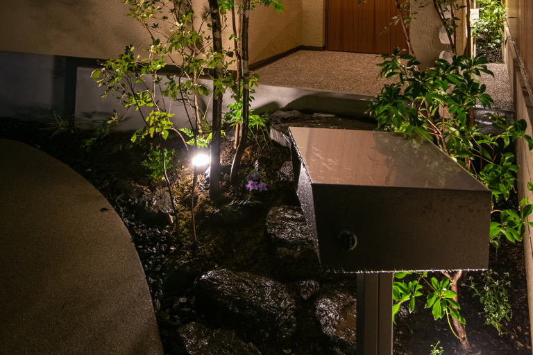 スポットライトに照らされた幻想的な植栽とアプローチ