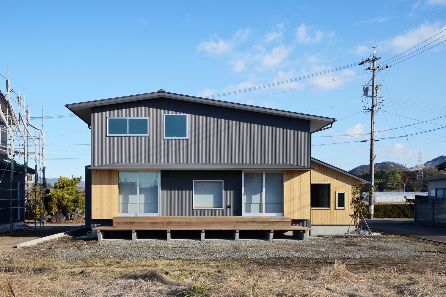 緩勾配の切妻屋根が建物全体の重心を抑えどっしりとした外観と広々としたウッドデッキ