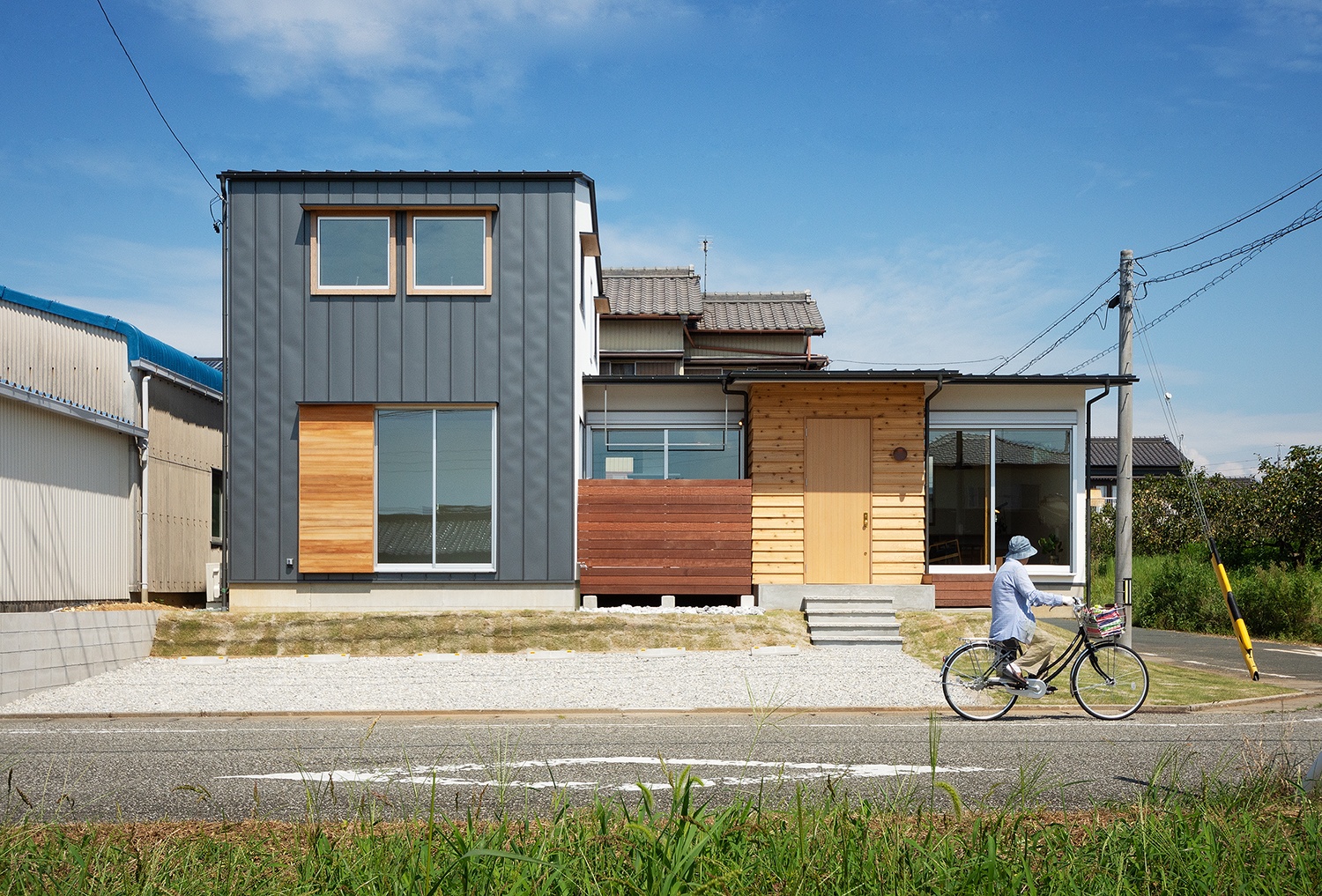 硬質な雰囲気の2階建て部分に、柔らかさ、素朴さを感じる平屋部分が接続された外観