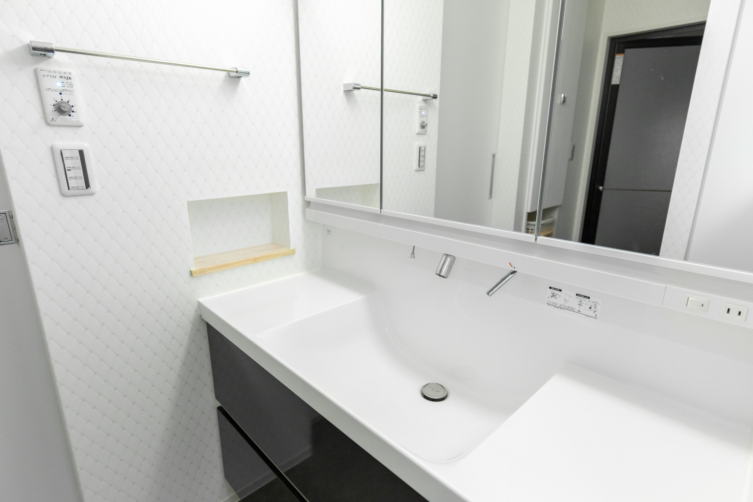 システム洗面台とニッチを設けたオシャレな洗面スペース。スイッチ上には全館換気のコントローラーを設置。