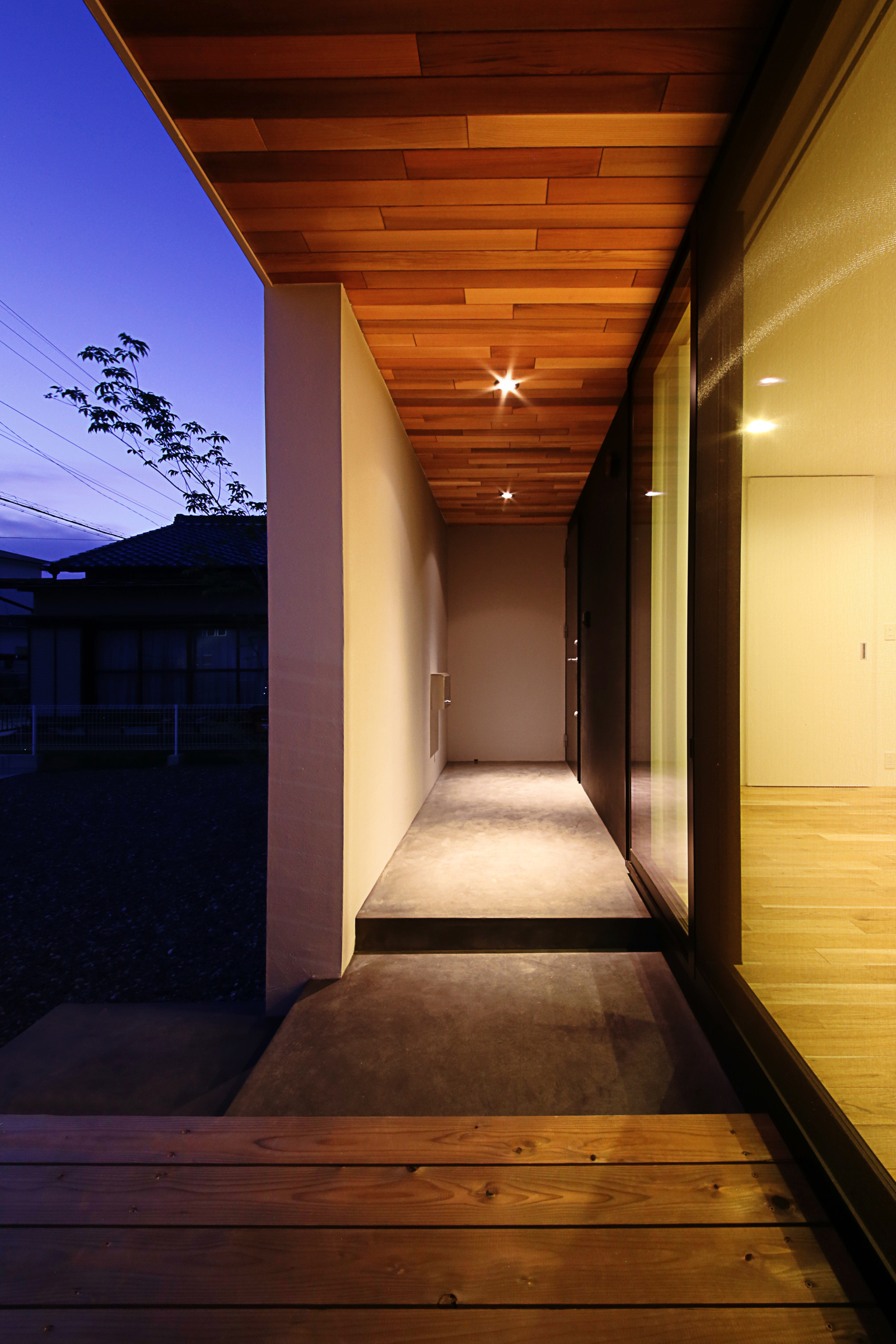 木製の天井とウッドデッキに囲まれた玄関アプローチ