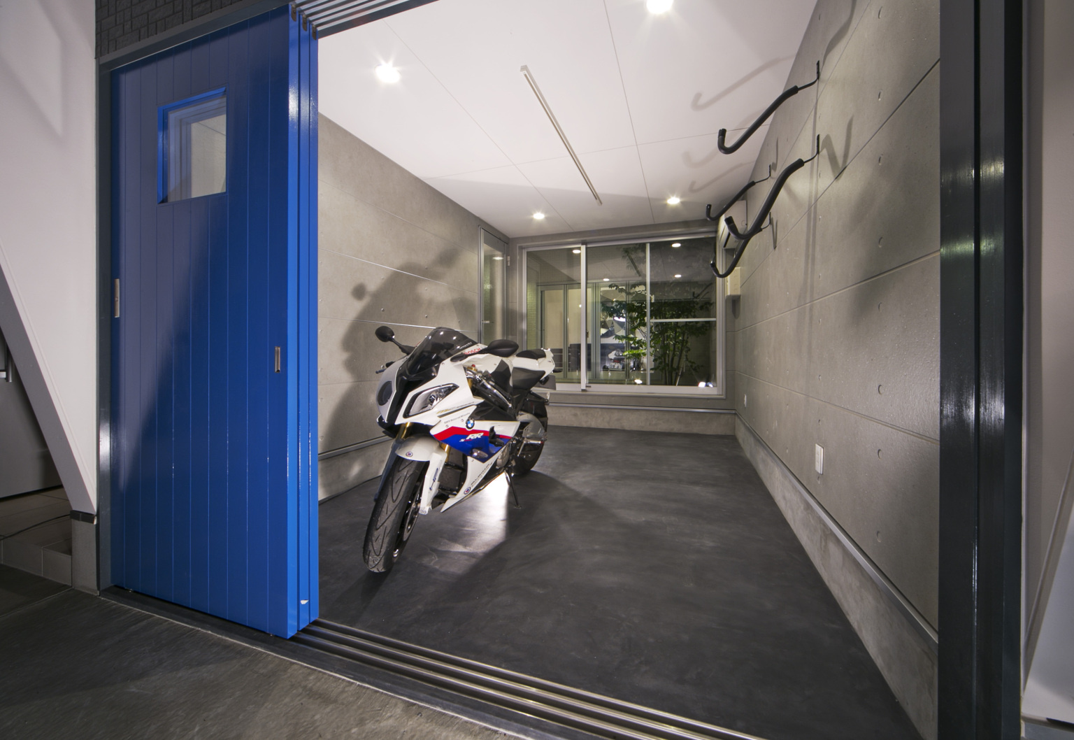 青い扉を建物のアクセントにし、駐車場を開放的な空間に演出