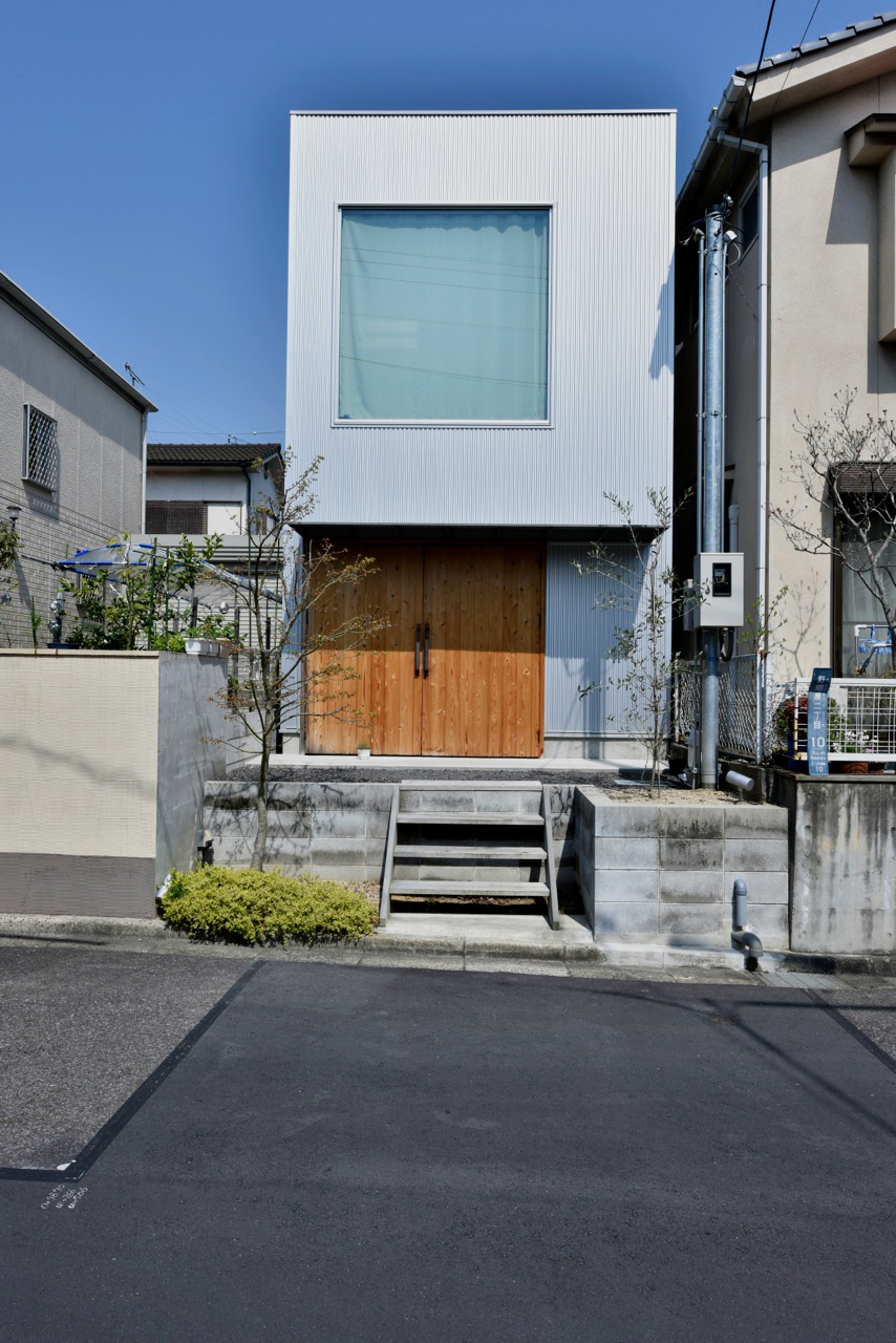 ガルバニウム鋼板の外壁にウッドの両開き戸の組み合わせが印象的な外観