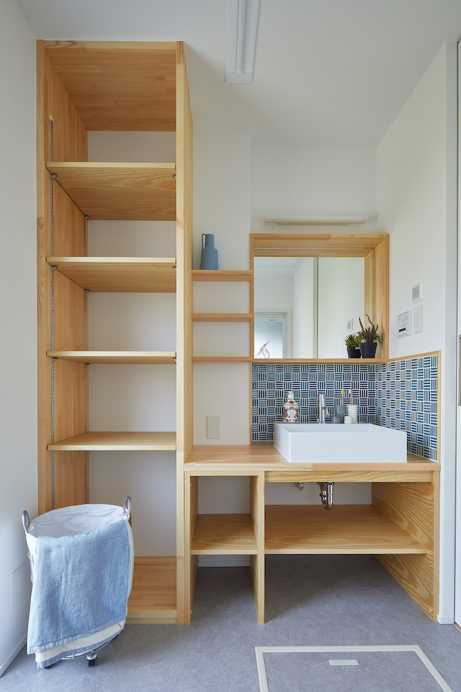 青タイルが映える洗面と収納量を誇る造作棚