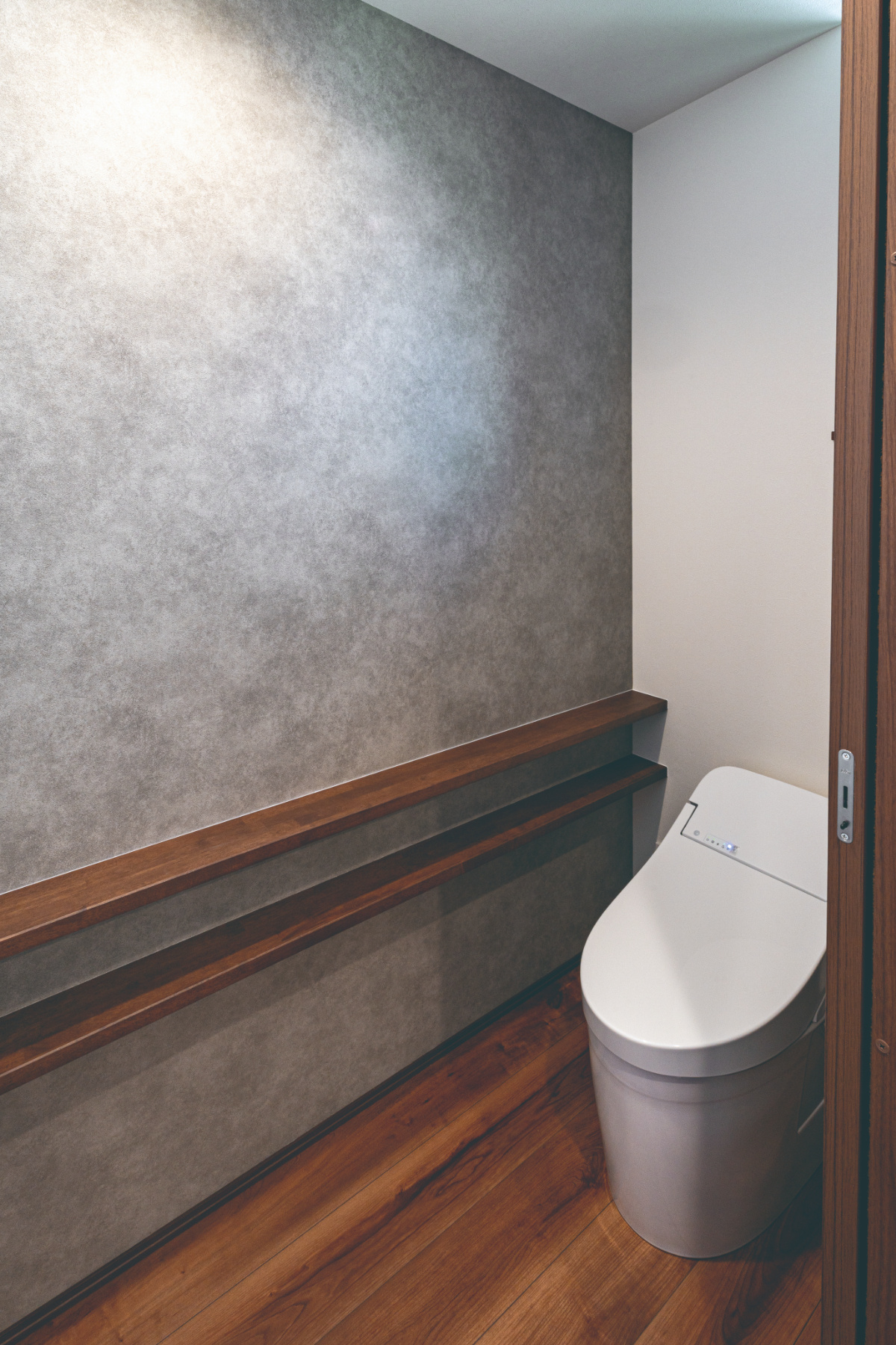 グレー壁紙×ダークブラウン木調棚のトイレ