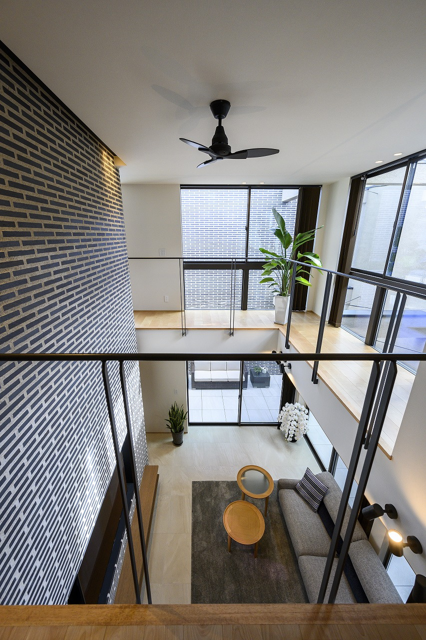 【大阪】吹き抜けに面して設けたタイル壁が印象的なリビング