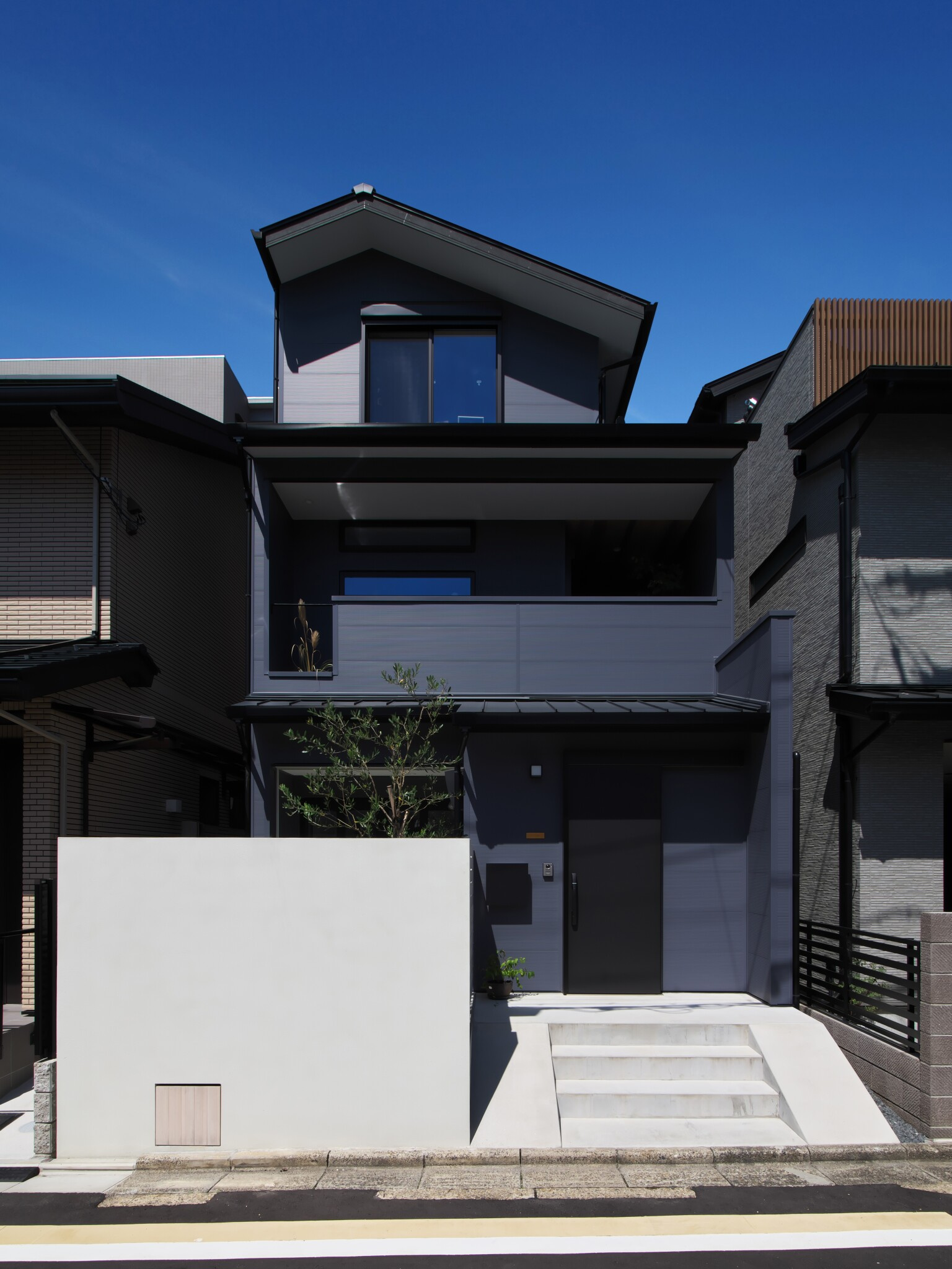 ネイビーの外壁と白い塀が爽やかな外観