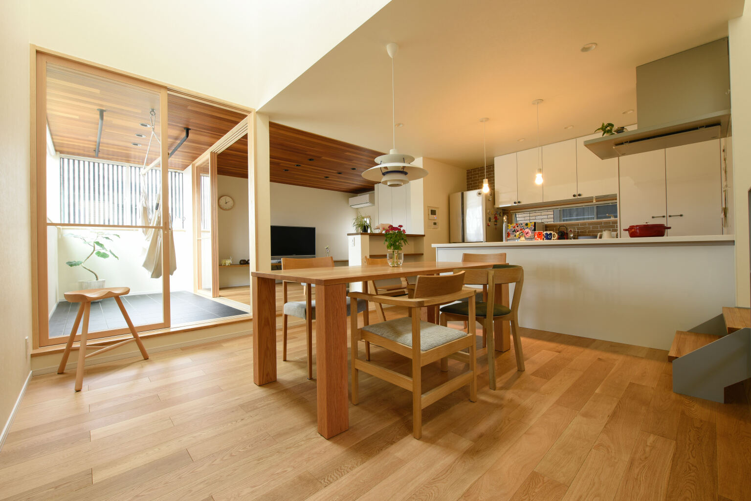 太陽光を取り込む中庭のような役割のサンルームと木の温かみあふれる狭小住宅のLDK