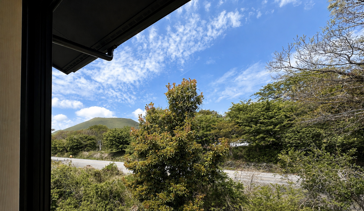 窓の先に広がる、大室山と伊豆の風景