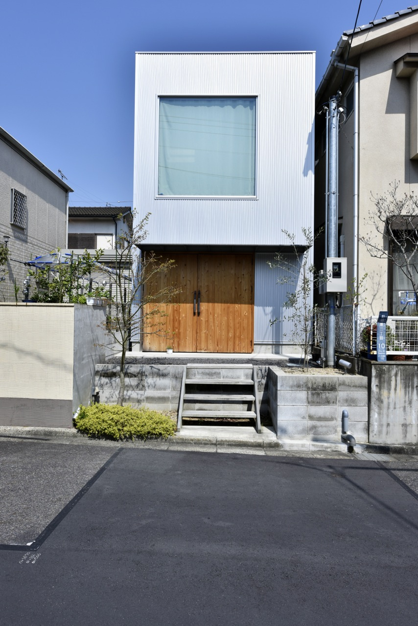 ガルバニウム鋼板の外壁にウッドの両開き戸の組み合わせが印象的な外観